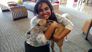 Young girl from India embracing the greyhound dog as the dog leans into her