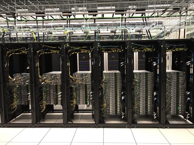 Wide angle view of five (5) compute cabinets. Note all the cabling required to connect the nodes to each other, to the storage systems and to the management nodes that control the flow of work dispatched by the SMU Research Community.