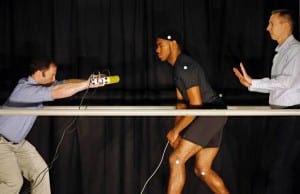 (From left) Researcher Ken Clark pushes student D'Marquis Allen as Peter Weyand waits to catch Allen during a demonstration on the physics of "flopping." Weyand, an associate professor of applied physiology and biomechanics at Southern Methodist University, is using technology to help understand how much force is necessary to knock an athlete off his or her feet. (Photo Dallas Morning News)