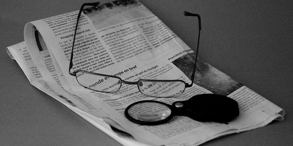 Reading Glasses and magnifying glass on top of news paper